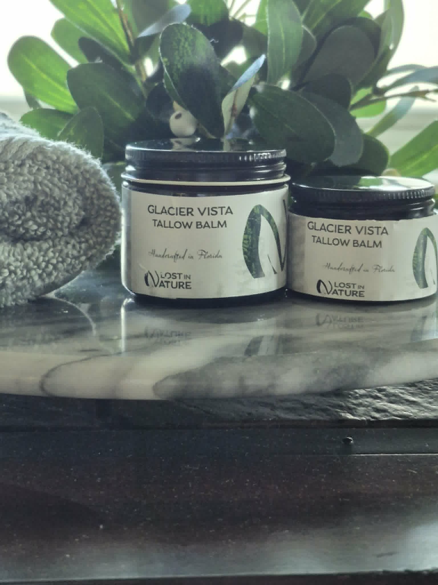 Two jars of Glacier Vista Tallow Balm arranged with greenery
